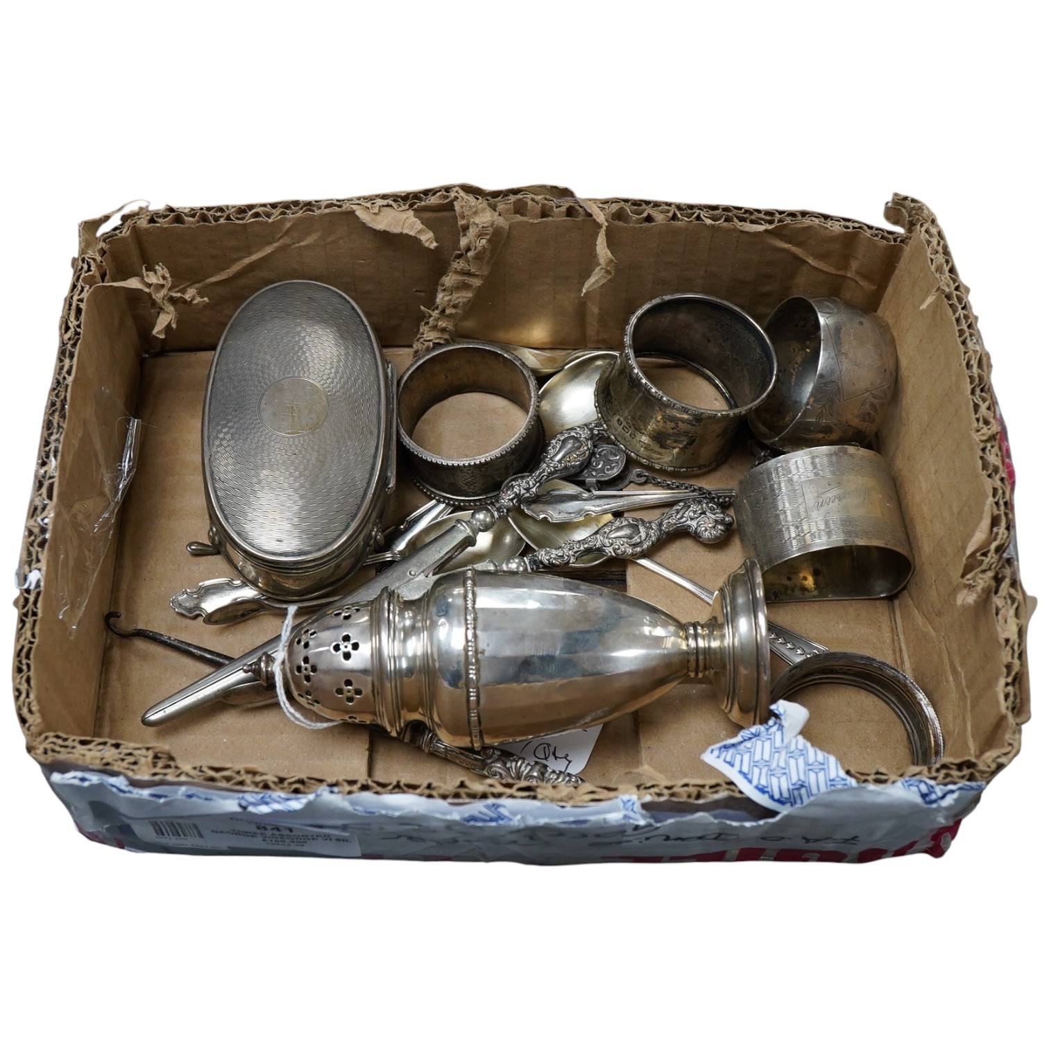 A small collection of silver including a George V mounted oval trinket box, Birmingham, 1916, 95mm, a sugar caster, five assorted napkin rings, five teaspoons, a pair of sugar tongs, handled glove stretchers and button h